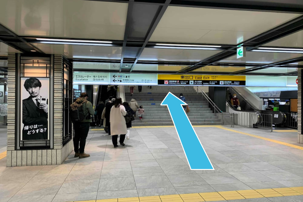 東出口改札を出て、階段またはエスカレータ－で上がります。そのまま斜め右方向に進みます。